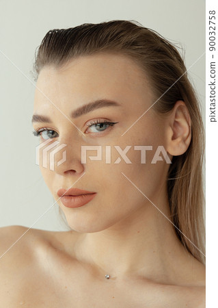 Close-up portrait of young beautiful woman with blonde hair and natural makeup posing isolated over grey studio background 90032758