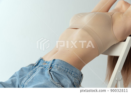Cropped image of slender female body, breast and belly isolated over grey studio background Cropped image of slender female body, breast and belly isolated over grey studio background 90032811