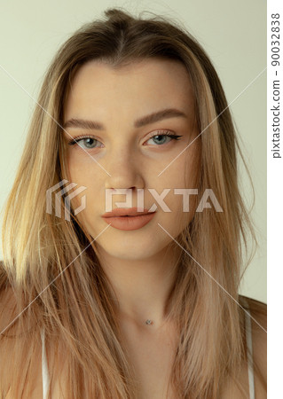 Close-up portrait of beautiful young blonde girl with natural makeup posing isolated over grey studio background Close-up portrait of beautiful young blonde girl with natural makeup posing isolated over grey studio background 90032838
