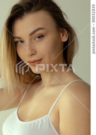 Close-up portrait of tender young blonde girl with natural makeup posing isolated over grey studio background Close-up portrait of tender young blonde girl with natural makeup posing isolated over grey studio background 90032839