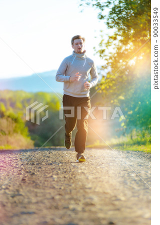 Man jogging in rural nature at beautiful summer day. Sport fitness model caucasian ethnicity training outdoor. Man jogging in rural nature at beautiful summer day. Sport fitness model caucasian ethnicity training outdoor. 90033549