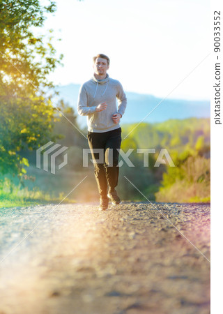 Man jogging in rural nature at beautiful summer day. Sport fitness model caucasian ethnicity training outdoor. Man jogging in rural nature at beautiful summer day. Sport fitness model caucasian ethnicity training outdoor. 90033552