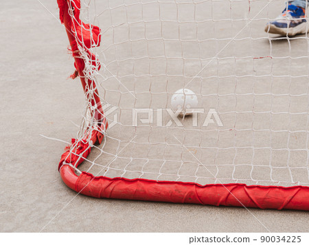 Floorball goal. Children playing outdoor in spring. Floor hockey players goalkeeper running with ball and sticks Floorball goal. Children playing outdoor in spring. Floor hockey players goalkeeper running with ball and sticks 90034225