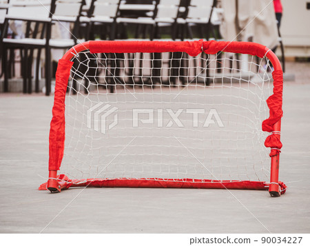 Floorball goal. Children playing outdoor in spring. Floor hockey players goalkeeper running with ball and sticks Floorball goal. Children playing outdoor in spring. Floor hockey players goalkeeper running with ball and sticks 90034227
