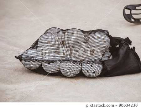 Floorball balls in bag. Children playing outdoor in spring. Floor hockey players goalkeeper running with ball and sticks Floorball balls in bag. Children playing outdoor in spring. Floor hockey players goalkeeper running with ball and sticks 90034230