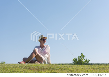 Woman lying and reading her favorite book on a meadow covered with fresh green grass on a sunny summer or spring day. Woman lying and reading her favorite book on a meadow covered with fresh green grass on a sunny summer or spring day. 90034734