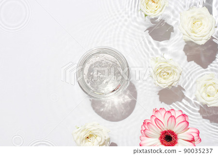 Jar of hydrating gel. Sunny white background with flowers and waves of water. 90035237