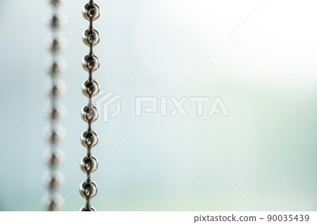 Close up a metal chain of a roller blind with blurred background for copy space. Close up a metal chain of a roller blind with blurred background for copy space. 90035439
