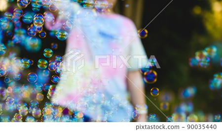Happy little boy standing and blowing soap bubbles on the outdoor field in summertime. Happy little boy standing and blowing soap bubbles on the outdoor field in summertime. 90035440