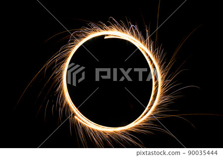 circle drawing light fireworks. Burning flare or flame with bright sparks on background with copy space. long exposure light painting. circle drawing light fireworks. Burning flare or flame with bright sparks on background with copy space. long exposure light painting. 90035444