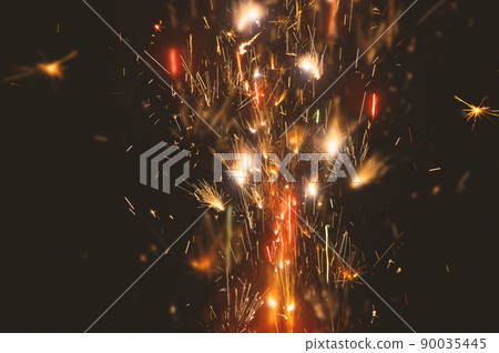 close up burning flare or flame with bright sparks and smoke on background with copy space. festive event concept. fireworks exploding at night. close up burning flare or flame with bright sparks and smoke on background with copy space. festive event concept. fireworks exploding at night. 90035445