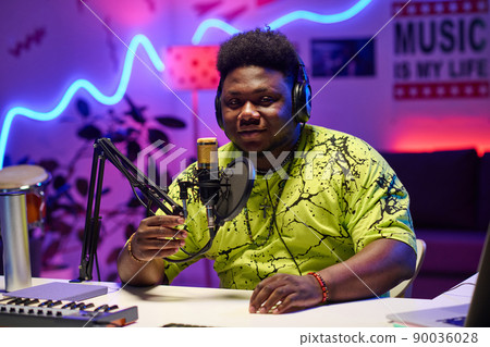 Young African American man wearing headphones adjusting microphone to start podcast or broadcast recording in home studio Young African American man wearing headphones adjusting microphone to start podcast or broadcast recording in home studio 90036028