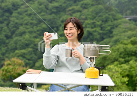 一個女人在戶外喝咖啡時看著她的智能手機 一個女人在戶外喝咖啡時看著她的智能手機 90036135