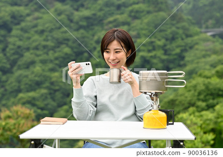 一個女人在戶外喝咖啡時看著她的智能手機 一個女人在戶外喝咖啡時看著她的智能手機 90036136