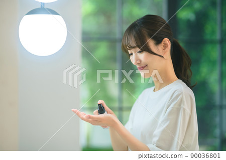 一位年輕女子一邊在浴室裡照鏡子一邊做皮膚護理 一位年輕女子一邊在浴室裡照鏡子一邊做皮膚護理 90036801