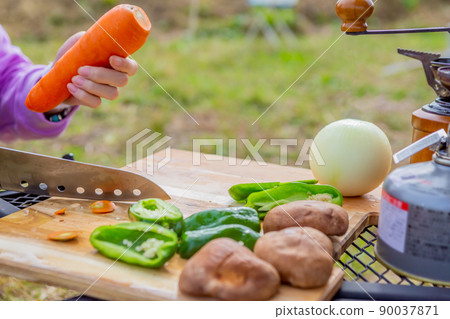 Close-up of a woman cutting vegetables to prepare for barbecue outdoors Close-up of a woman cutting vegetables to prepare for barbecue outdoors 90037871