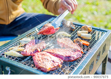 A close-up of a barbecue that is placed outdoors on a wire mesh to bake meat. A close-up of a barbecue that is placed outdoors on a wire mesh to bake meat. 90037873