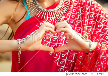 Beautiful indian woman in red saree hands the symbol of the heart on the beach.Valentine's Day love and faith Beautiful indian woman in red saree hands the symbol of the heart on the beach.Valentine's Day love and faith 90037999