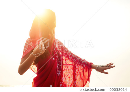 indian female model in vacation on paradise tropical beach by ocean sea. hindu woman with kundan jewelry traditional India costume red wedding sari.asian girl near the rocks shores of Indian Ocean bay 90038014