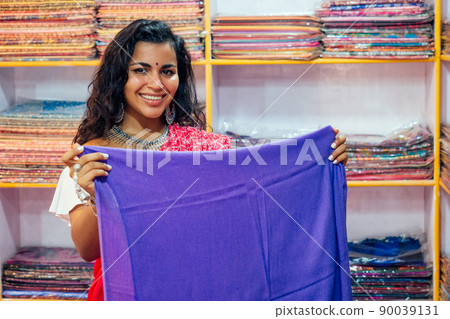 business lady in red traditional sari and jewelery clothes shop owner cashmere yak wool shawls.female seller in goa india arambol sale shop.designer seamstress tailor girl choosing fabric 90039131