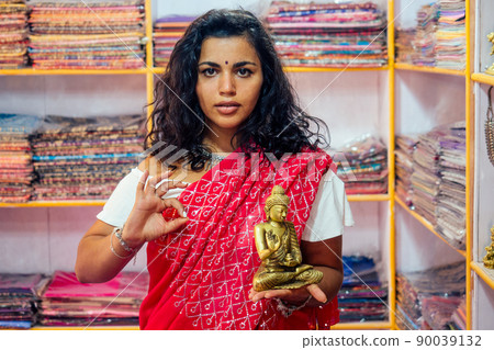 business lady indian seller tradition red sari souvenir shop buddha shiva figurine yoga meditation.girl in india in the religion store.beautiful woman with bijouterie jewelry earrings Delhi Bazaar 90039132