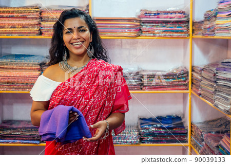 business lady in red traditional sari and jewelery clothes shop owner cashmere yak wool shawls.female seller in goa india arambol sale shop.designer seamstress tailor girl choosing fabric 90039133