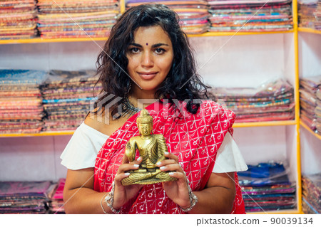 business lady indian seller tradition red sari souvenir shop buddha shiva figurine yoga meditation.girl in india in the religion store.beautiful woman with bijouterie jewelry earrings Delhi Bazaar 90039134