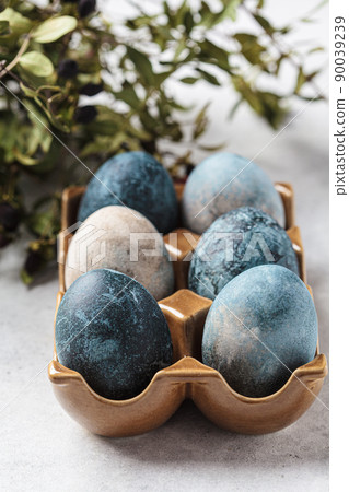 Easter eggs painted in trendy denim blue in brown stand, gray background. 90039239