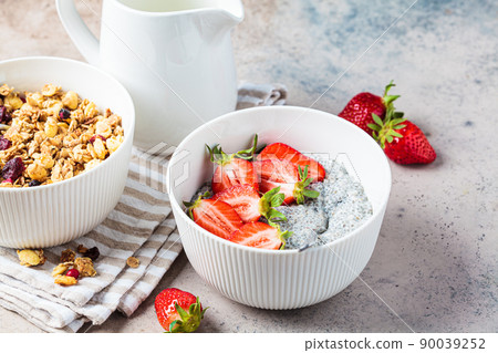 Homemade granola bowl and chia pudding with strawberries, gray background. Homemade granola bowl and chia pudding with strawberries, gray background. 90039252