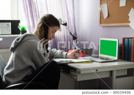 Green screen. A student sits at a desk doing schoolwork. Green screen. A student sits at a desk doing schoolwork. 90039496