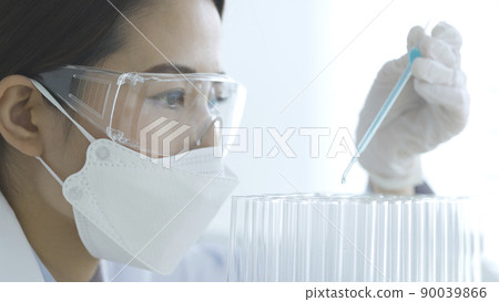 Female experiment in a white coat doing research 90039866