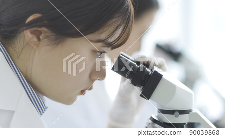 一個穿白大褂的女人透過顯微鏡看 90039868
