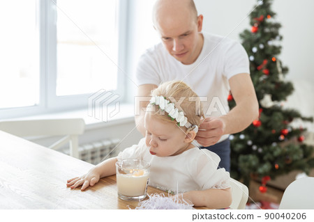 Father helps to put on cochlear implant for his deaf baby daughter in christmas living room copy space. Diversity and hearing aid and innovating medical technologies treatment deafness concept 90040206