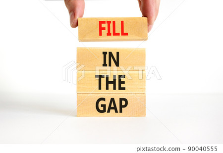 Fill in the gap symbol. Concept words Fill in the gap on wooden blocks on a beautiful white table white background. Businessman hand. Business, motivational and fill in the gap concept. 90040555