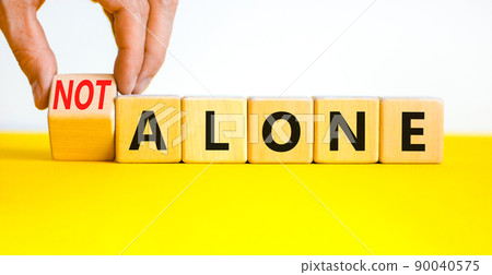 You are not alone symbol. Businessman turns wooden cubes and changes concept words alone to not alone. Beautiful white background. Business, support and you are not alone concept. Copy space. You are not alone symbol. Businessman turns wooden cubes and changes concept words alone to not alone. Beautiful white background. Business, support and you are not alone concept. Copy space. 90040575