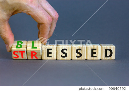 Blessed or stressed symbol. Businessman turns wooden cubes and changes the concept word Stressed to Blessed. Beautiful grey table grey background. Business blessed or stressed concept. Copy space. 90040592
