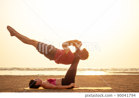 two young man and beautiful woman on beach doing fitness yoga exercise together. Acroyoga element for strength and balance at sea octan goa india sunset 90041794
