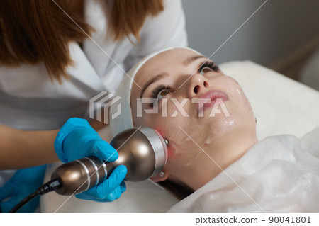 LED light anti-aging mask for facial skin care in a spa slow motion. A woman lies on a couch in a special mask. Modern technologies of beauty and health. LED light anti-aging mask for facial skin care in a spa slow motion. A woman lies on a couch in a special mask. Modern technologies of beauty and health. 90041801