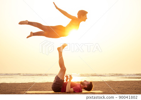 Two people practicing yoga in the sunset light on goa india beach. female and male acro yogi tantra flying copyspce Two people practicing yoga in the sunset light on goa india beach. female and male acro yogi tantra flying copyspce 90041802