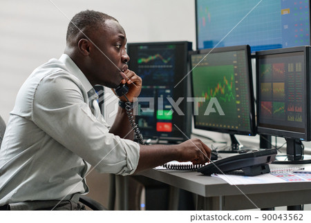 Young African American man working in brokerage company having problems speaking about issue on phone 90043562