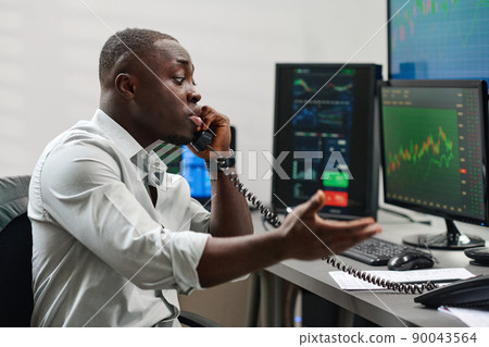 Emotional young African American man working in brokerage agency having problems with client trying to explain situation on phone Emotional young African American man working in brokerage agency having problems with client trying to explain situation on phone 90043564