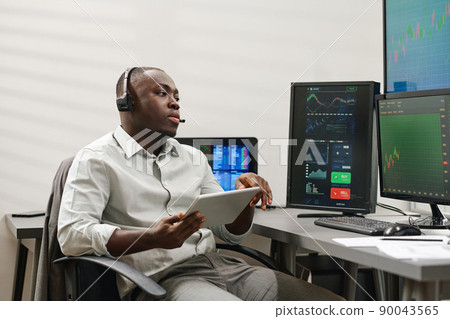 African American man holding digital tablet working with clients advising them best stocks to buy and sell 90043565