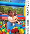 Baby girl lying down in colourful balls with mother 90043721