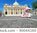 Baby girl sitting on a european city street. Little child outdoors in a town. 90044160