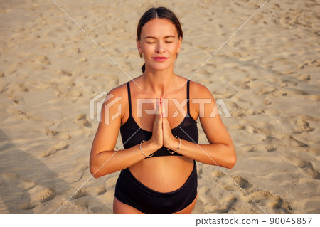 Pregnant woman on the beach doing yoga Pregnant woman on the beach doing yoga 90045857