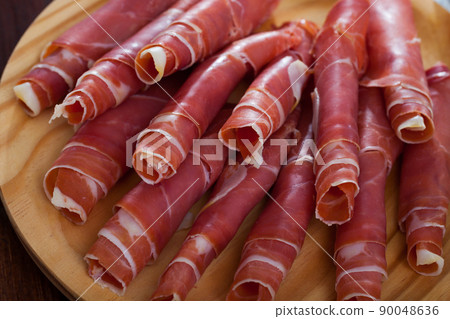Spanish tasty meal rolls of prosciutto di parma at wooden desk Spanish tasty meal rolls of prosciutto di parma at wooden desk 90048636
