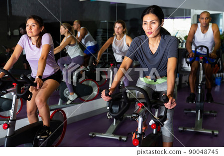 Woman training on cycling machine in gym Woman training on cycling machine in gym 90048745