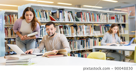 Couple of students spending time together in library 90048830