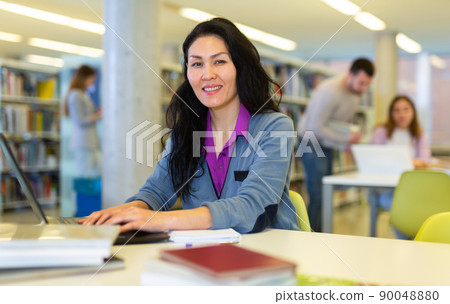 Focused woman working on laptop at library Focused woman working on laptop at library 90048880