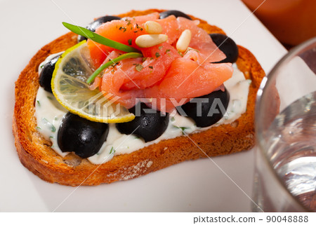 Toasted bread with creamy sauce, salmon and olives 90048888